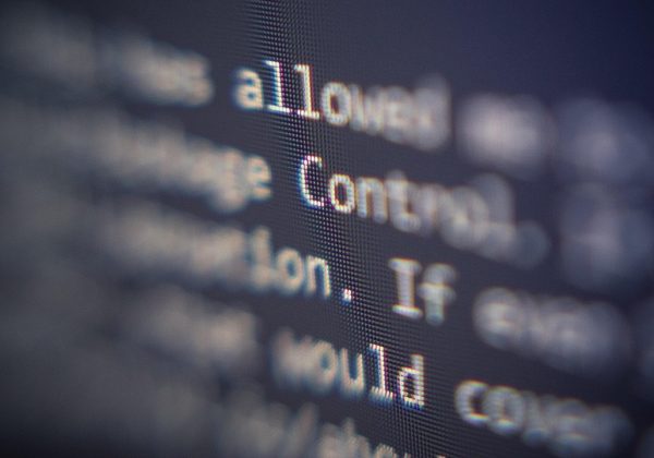 工作室里两块并排的显示器分别显示海报排版与字体授权条款文档，桌面散落打印样张